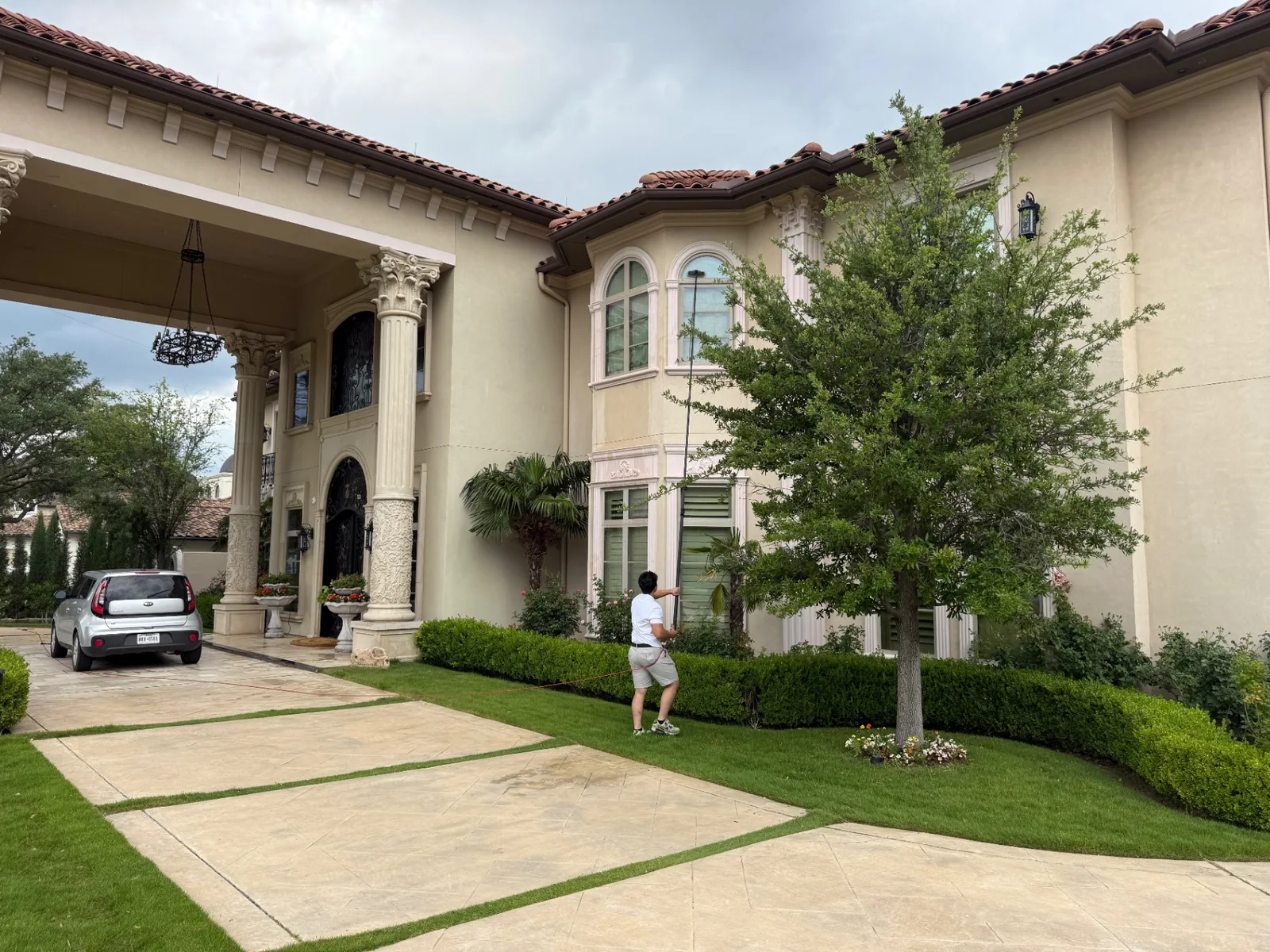 Technician cleaning multi-story arched windows at a Mediterranean estate in Dallas, TX