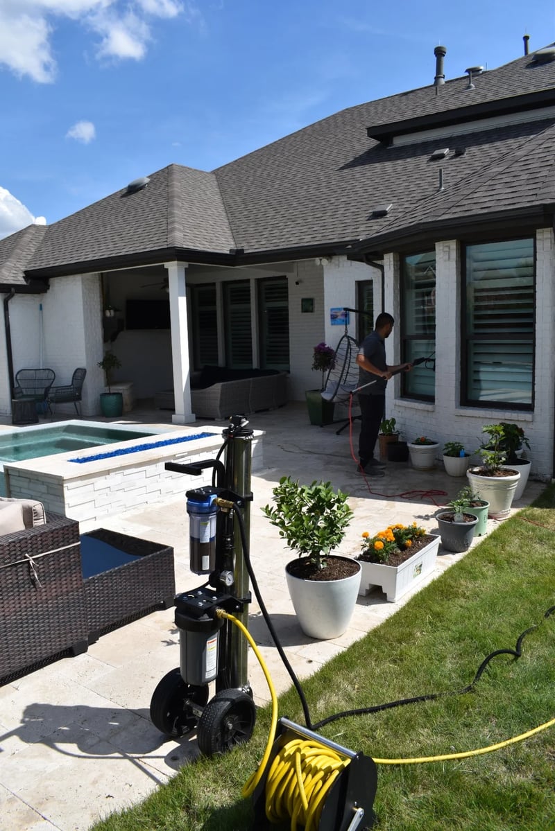 Technician using pure-water window cleaning equipment beside a residential pool in Dallas-Fort Worth