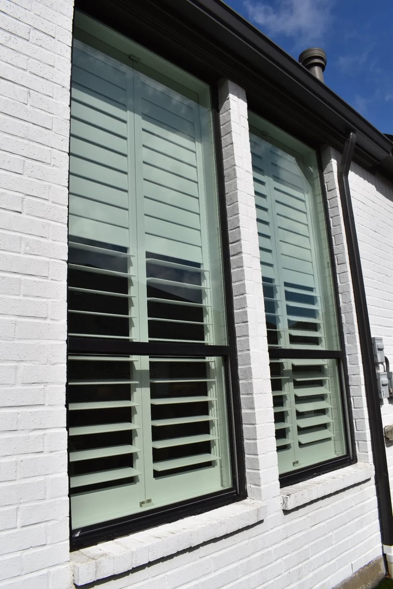 Tall professionally cleaned windows with plantation shutters on a white-brick Dallas home
