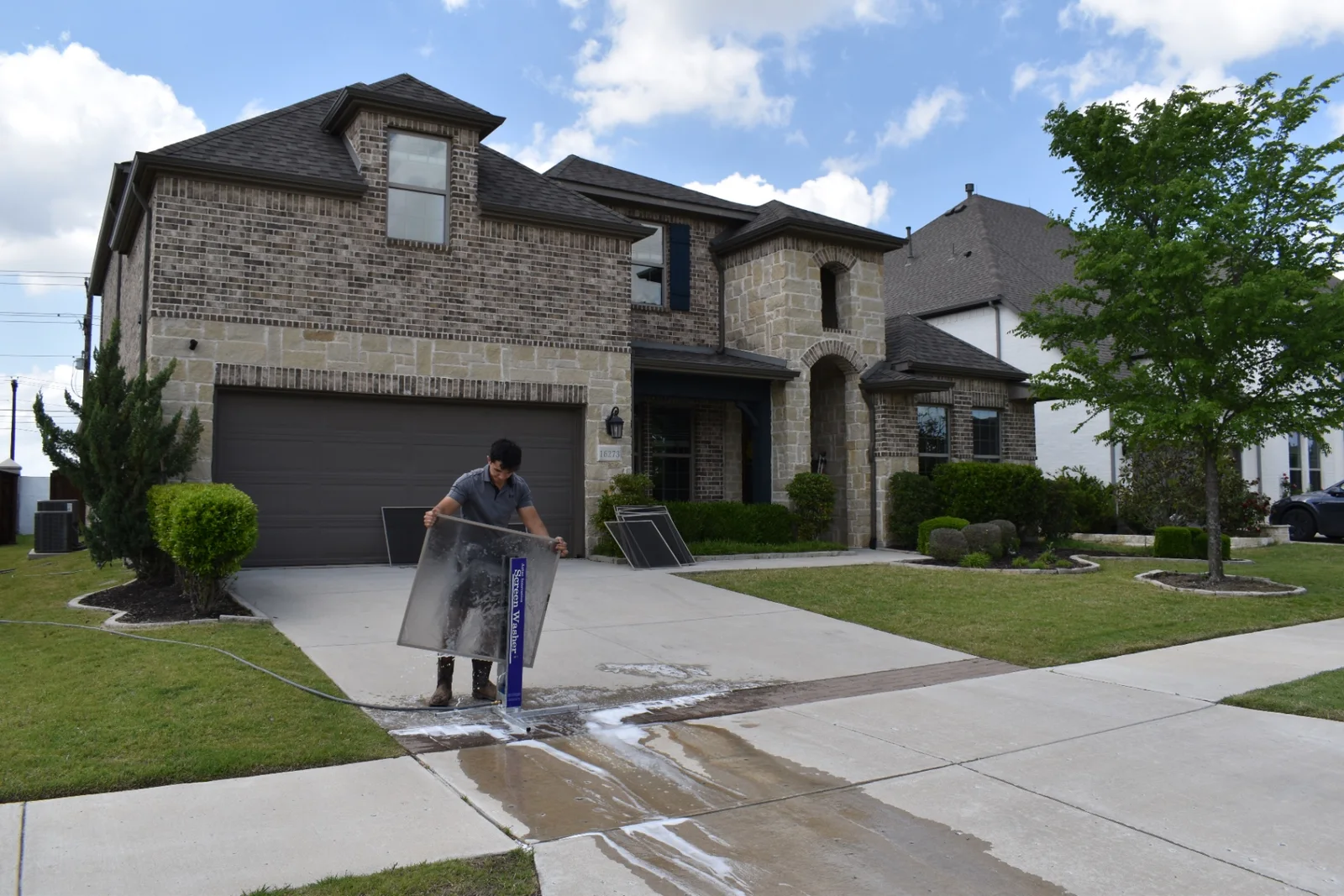Technician cleaning window screens at a brick-and-stone luxury home in Dallas-Fort Worth