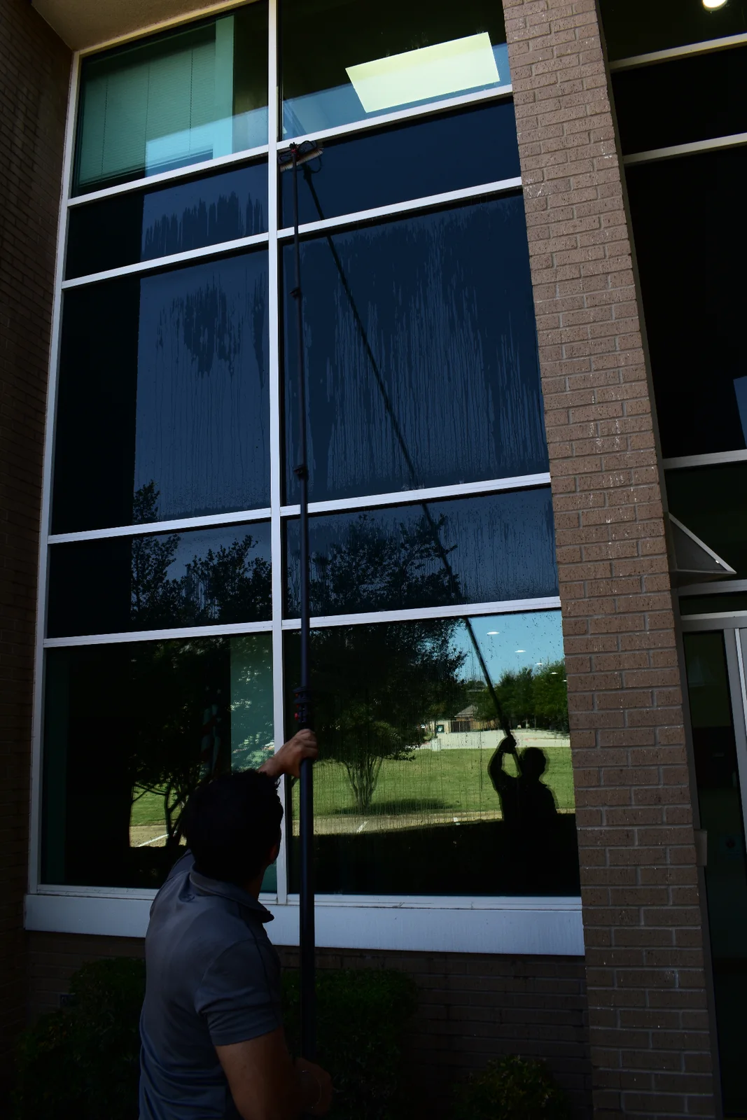 Technician cleaning high commercial glass with a pure-water pole in the Dallas-Fort Worth metroplex