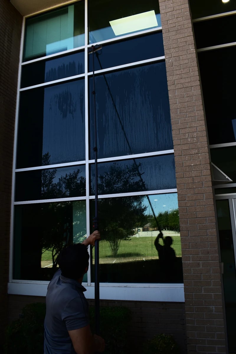 Technician cleaning high commercial glass with a pure-water pole in the Dallas-Fort Worth metroplex