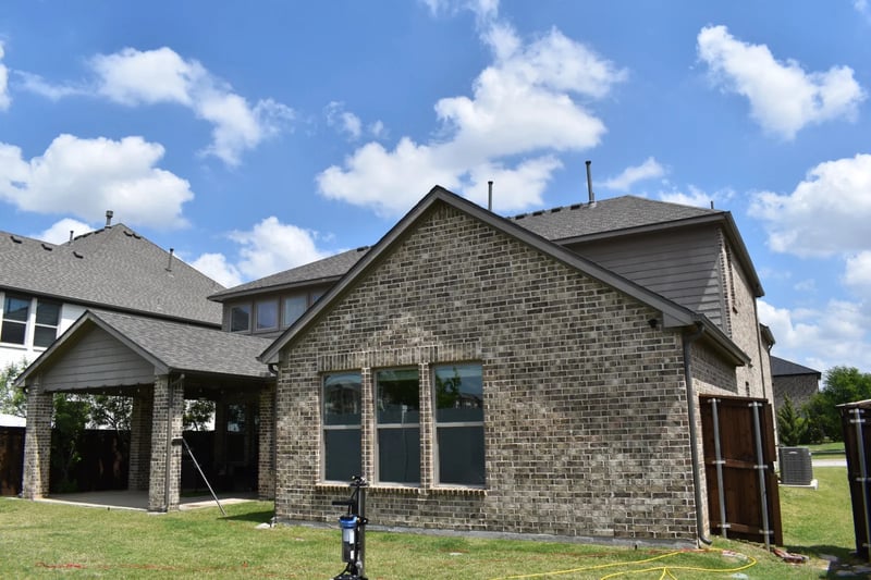 Water-fed window cleaning equipment outside a brick residence in Dallas, TX