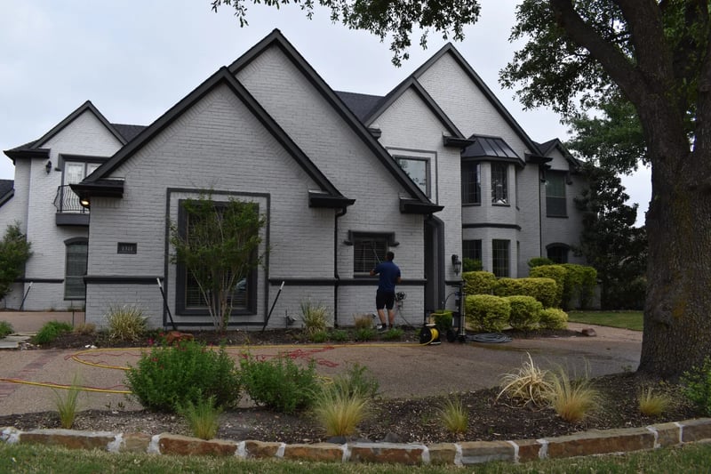 Professional window cleaning in progress at a luxury white brick estate in North Dallas, TX
