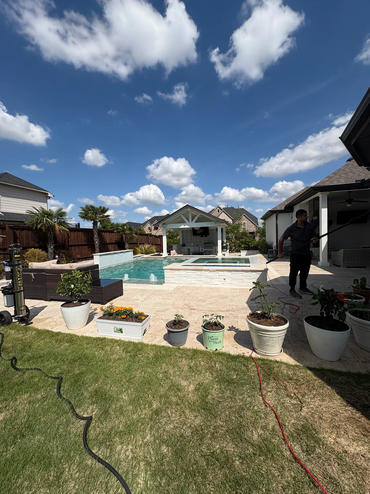Technician cleaning residential windows beside a luxury pool in Dallas-Fort Worth