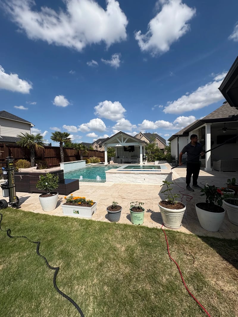 Technician cleaning residential windows beside a luxury pool in Dallas-Fort Worth