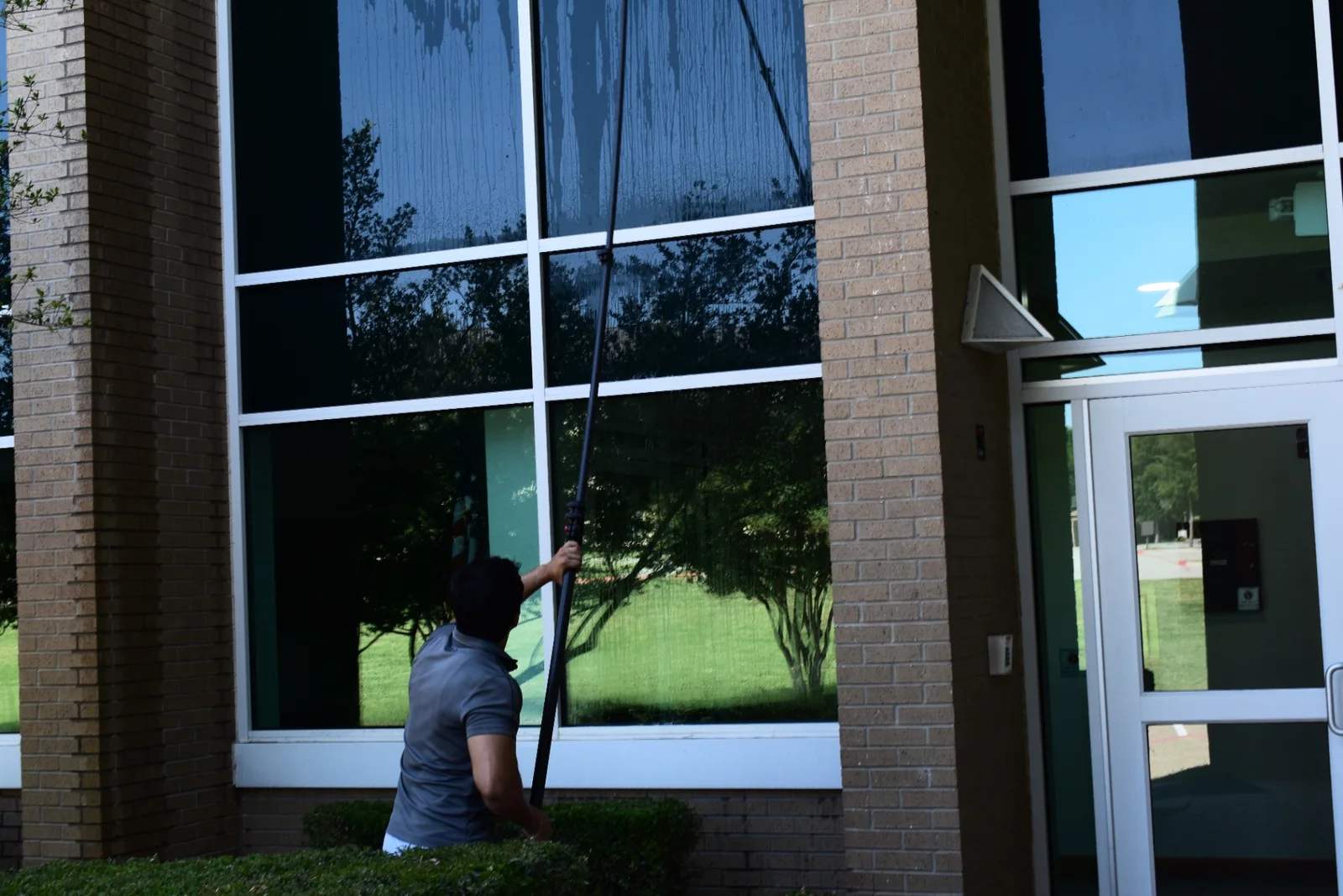 Professional water-fed pole cleaning on multi-story commercial windows in Dallas-Fort Worth