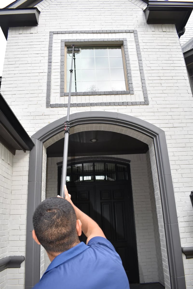 Technician using a water-fed pole to clean a high entry window at a Dallas luxury home