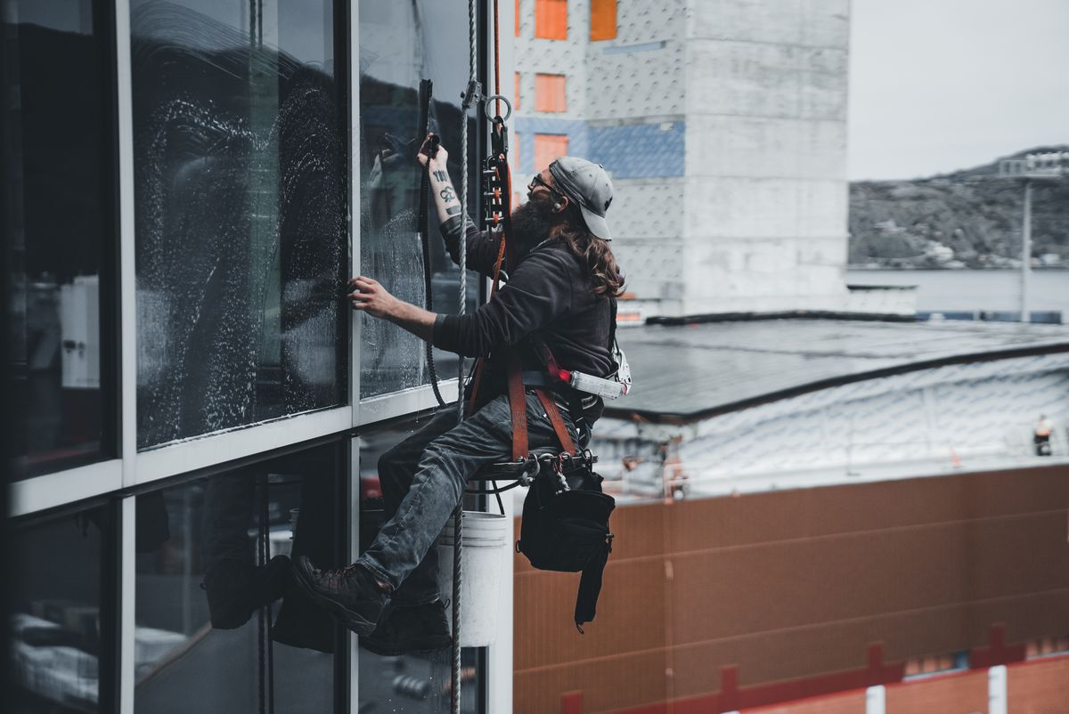 Harnessed technician safely cleaning windows on an upper story
